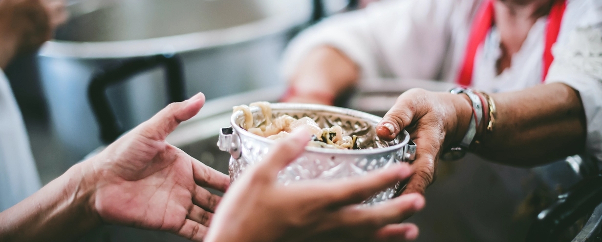 Photo of someone's hands reaching for a bowl of food