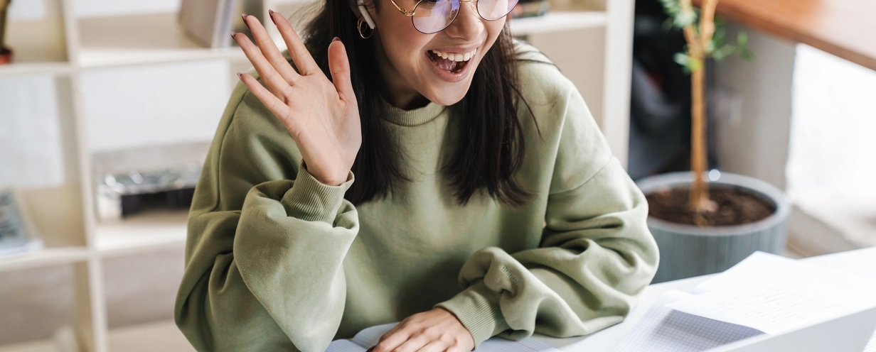 woman waving at laptop screen