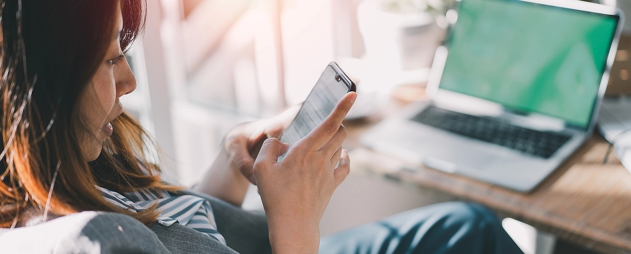 Woman sitting at desk looking at mobile phone