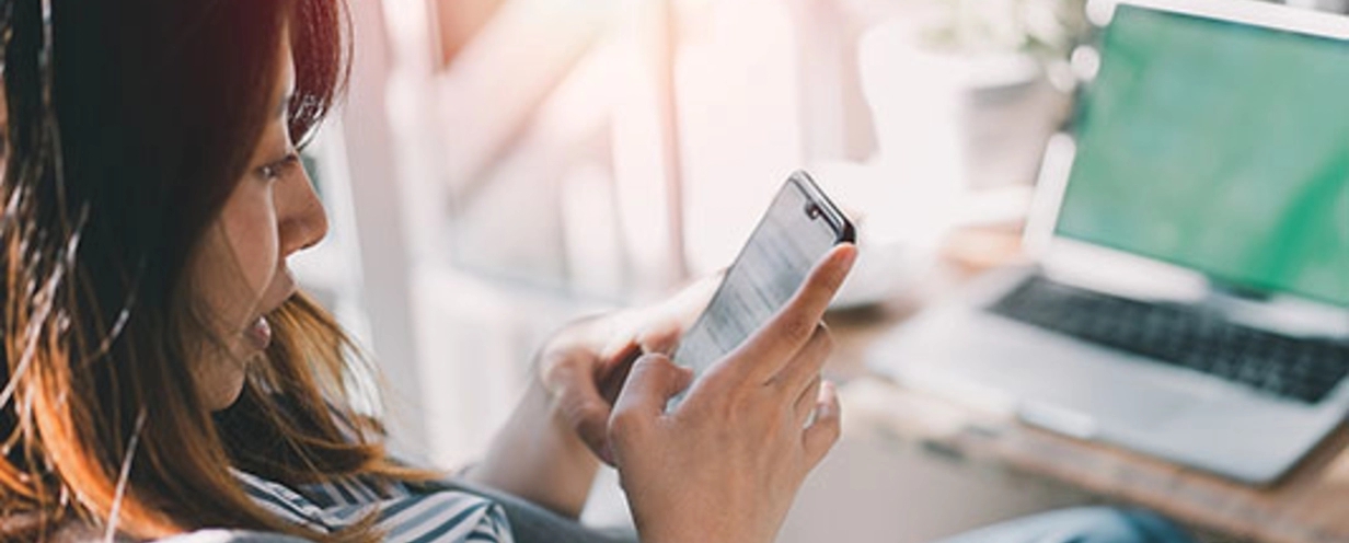 Woman sitting at desk looking at mobile phone