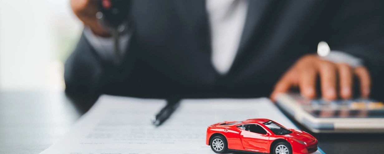 Red toy car on a desk with a person out of focus in background