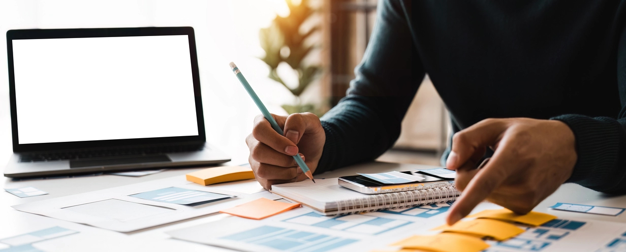 Image of a person sitting at a table reviewing documents with a pencil in hand 