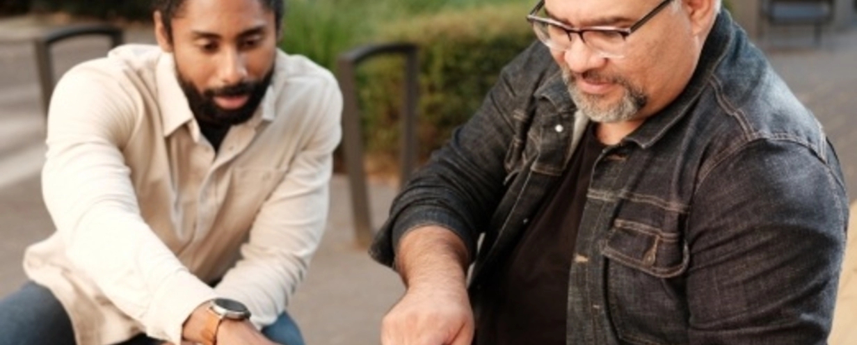 two men pointing at a laptop