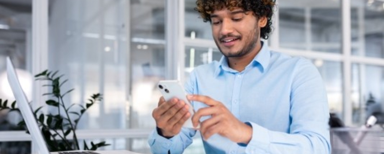 Business professional using their phone while in front of their laptop