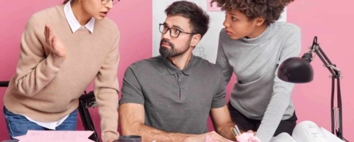 Three people talking to each other in a pink office