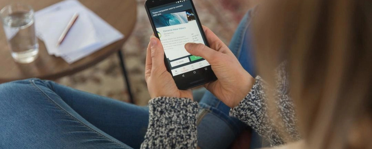 Photo of a woman sitting on a couch looking at a mobile phone