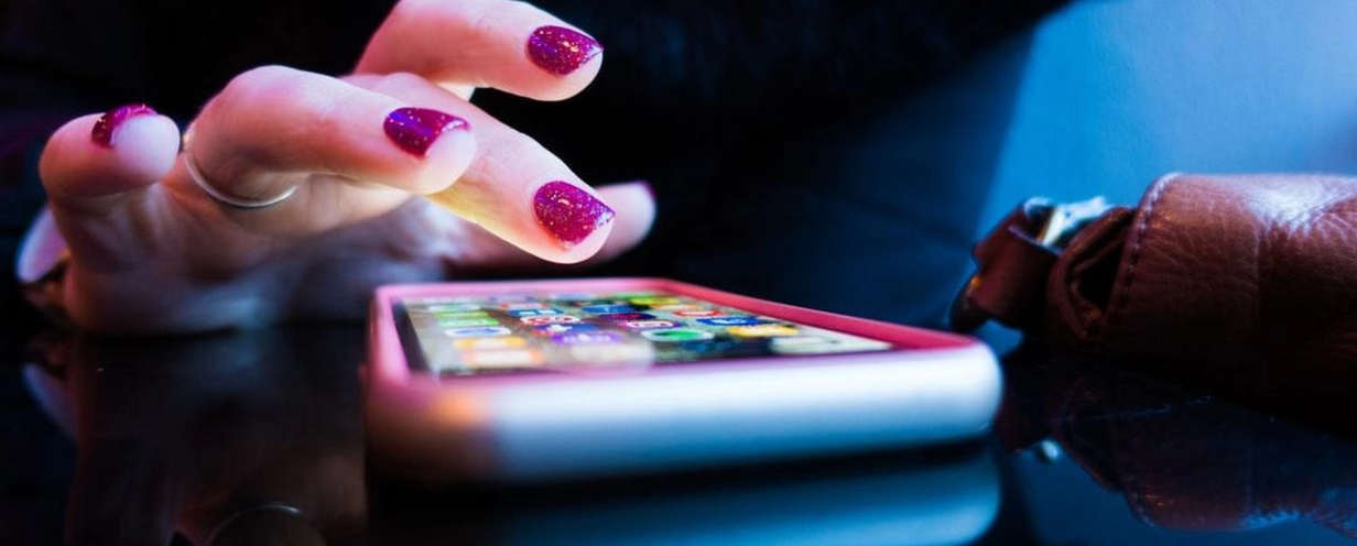 Woman's hand tapping on an illuminated mobile phone