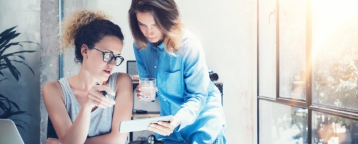 Two women discuss over a tablet.