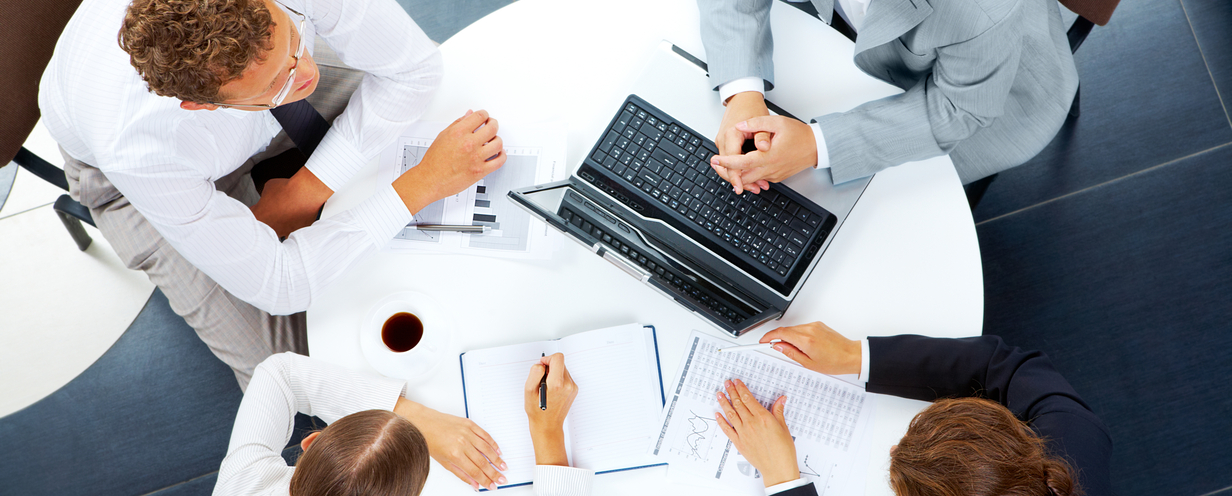 Top down view of 4 colleagues at a round desk in a meeting