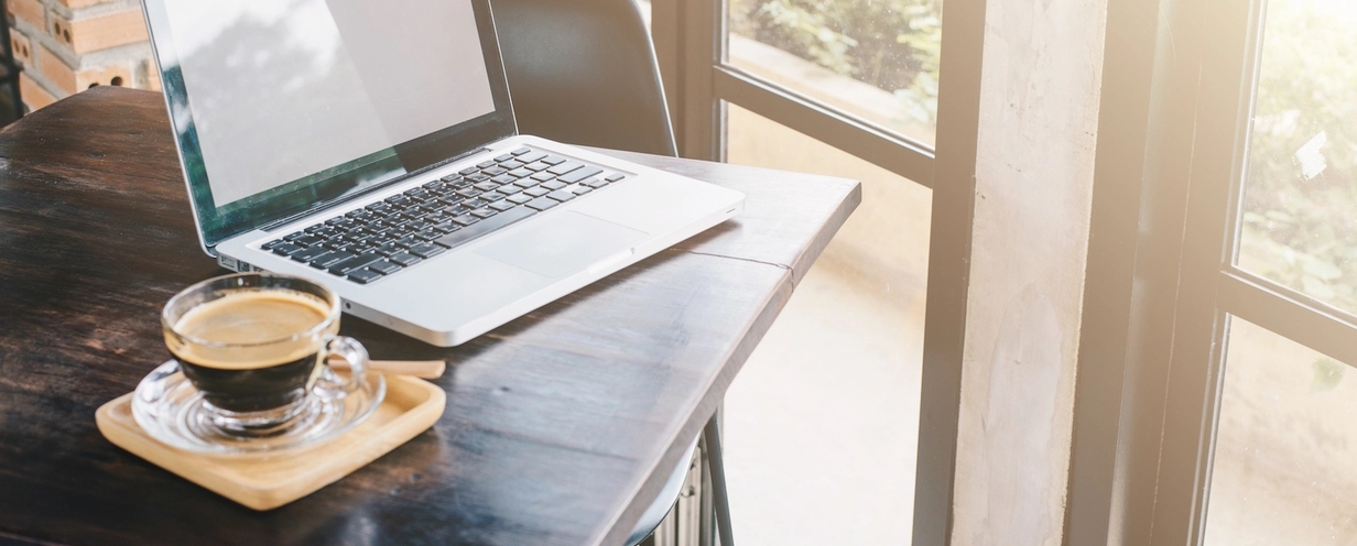 Photo of laptop and cup of coffee on a table