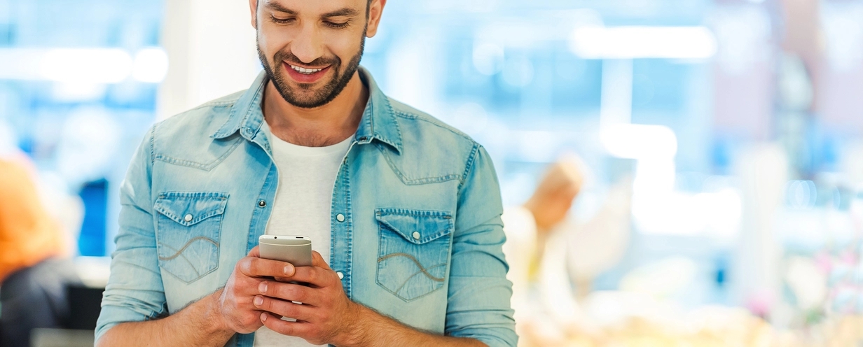 Man looking at his mobile phone while shopping