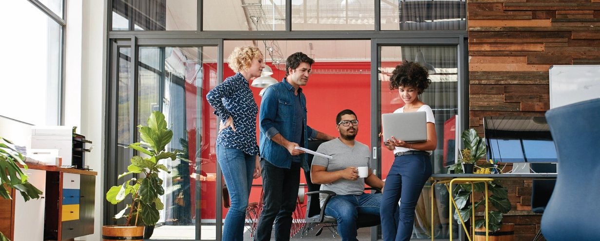 Photo of a design team gathered around a computer working on a website redesign