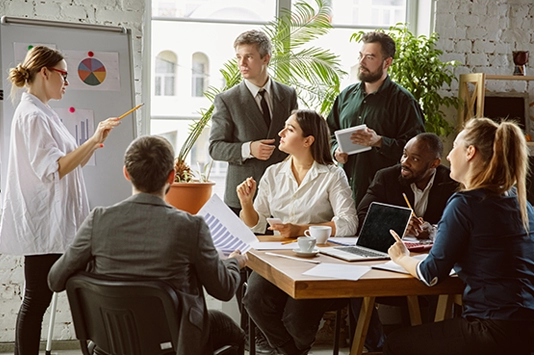 Group of business people collaborating around a conference table, actively discussing ideas and reviewing documents, exemplifying the lean UX process in a modern office setting.