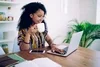 Photo of a person looking at their laptop while holding a white mug