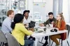 5 young professionals sitting at a table in an open office