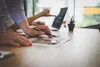 Photo showing hands of someone reviewing a wireframe on paper and on mobile device