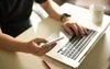 Image of a person sitting at a desk with a coffee mug, laptop, and cell phone