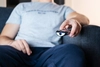 Photo of a person sitting on a couch pointing television remote 