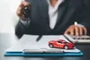 Red toy car on a desk with a person out of focus in background