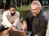 two men pointing at a laptop