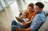 Family of three sitting together while looking at a tablet