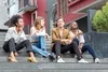 Group of young adults sitting on steps outside in front of a building