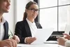 Photo of 3 professionals sitting at a conference table and smiling