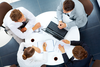 Top down view of 4 colleagues at a round desk in a meeting