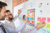 Two men brainstorm a design on a white board.