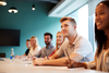 Group of young individuals sitting at a boardroom table watching a speaker present