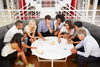 Photo of 7 professional colleagues seated around a circular coffee table looking at marketing campaign