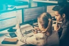 Photo of two professionals sitting in front of multiple computer monitors