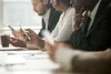 Photo of a group of office workers at a conference room table using their mobile phones