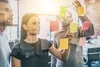 Photo of 3 business people reviewing sticky notes on a window wall