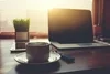 Photo of a laptop on a desk with a cup of hot coffee