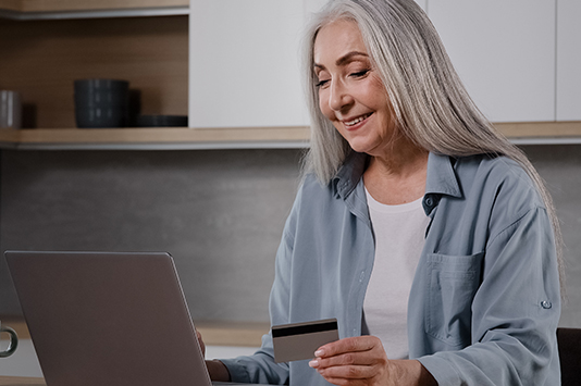 Woman holding credit cart looking at laptop