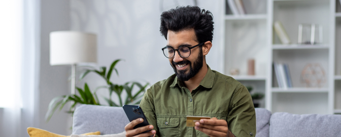 BLOG-Male-using-banking-app-on-sofa-happy-and-smiling BLOG-Male-using-banking-app-on-sofa-happy-and-smiling