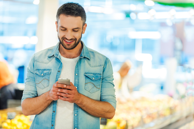 Man looking at his mobile phone while shopping